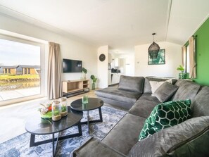 A modern living room with a large sofa, a coffee table, and a flat-screen TV. - Vakantiepark Aan de Maas - Maas Lande | 4p by Interhome (Kerkdriel)