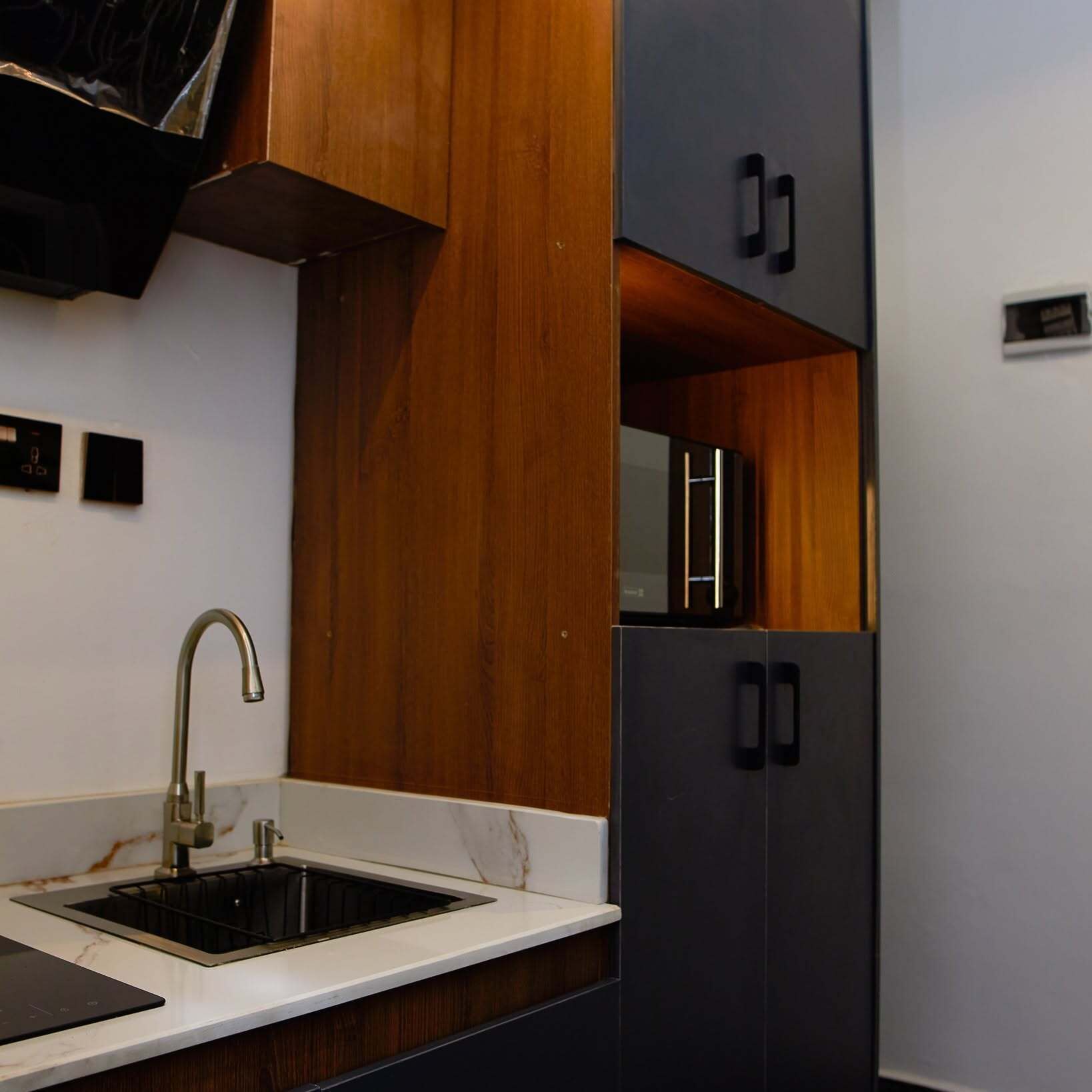 Una cocina moderna con un lavamanos integrado, armarios de madera y un refrigerador negro.