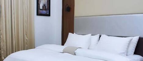 A hotel room with a bed, a wall-mounted air conditioner, and a framed picture.
