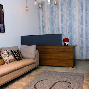 Una sala de estar moderna con un sofá, un mostrador de recepción de madera y una alfombra estampada.
