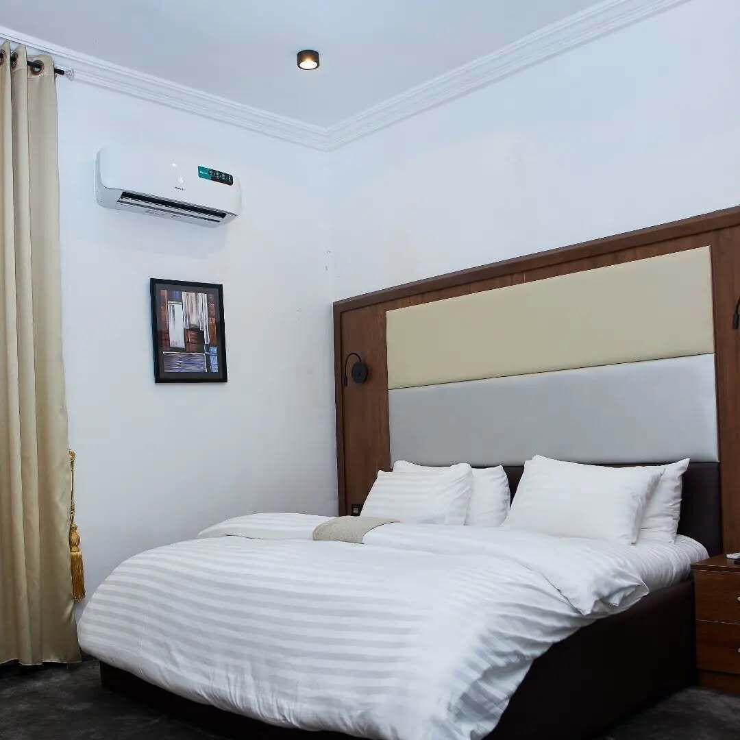 Habitación de hotel con una cama, aire acondicionado de pared, un cuadro enmarcado y una lámpara en el techo.