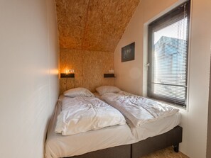 Ein kleines Schlafzimmer mit Etagenbett, einem Fenster mit Jalousien und zwei Wandleuchten.