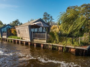 Ein Holzhausboot mit einem Balkon, gelegen auf einem Gewässer.