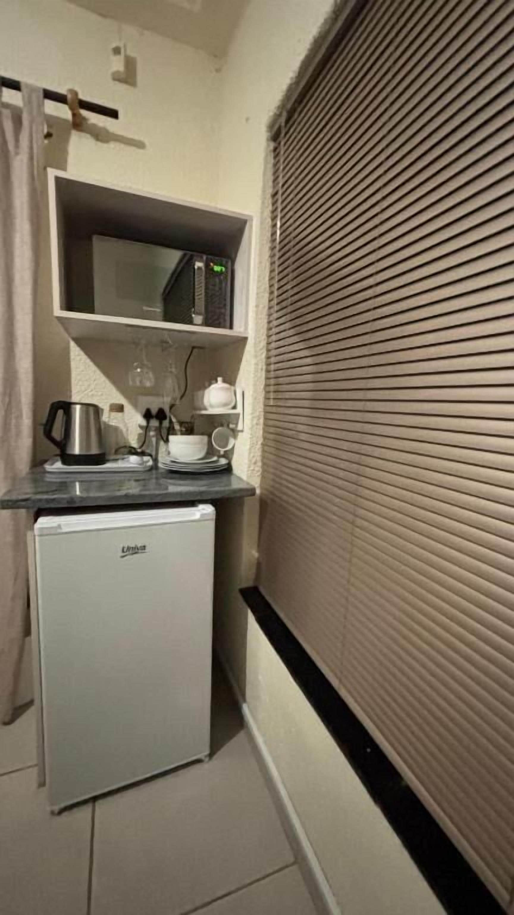 A compact kitchenette with a microwave, kettle, and small refrigerator.