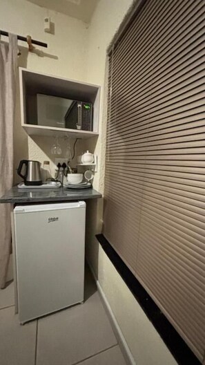 A compact kitchenette with a microwave, kettle, and small refrigerator.