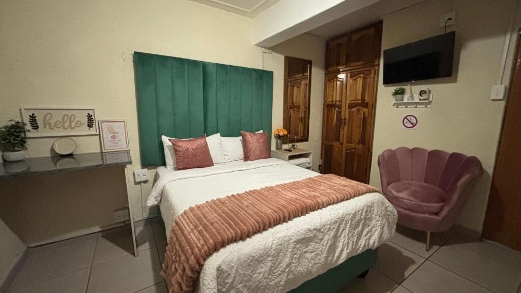 Un dormitorio con una cama, una silla, un televisor y un cartel con la palabra 'hello'.