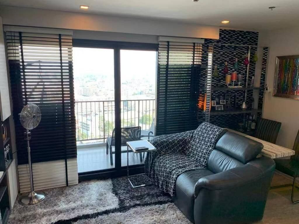 A modern living room with a leather sofa, a small table, and a fan.