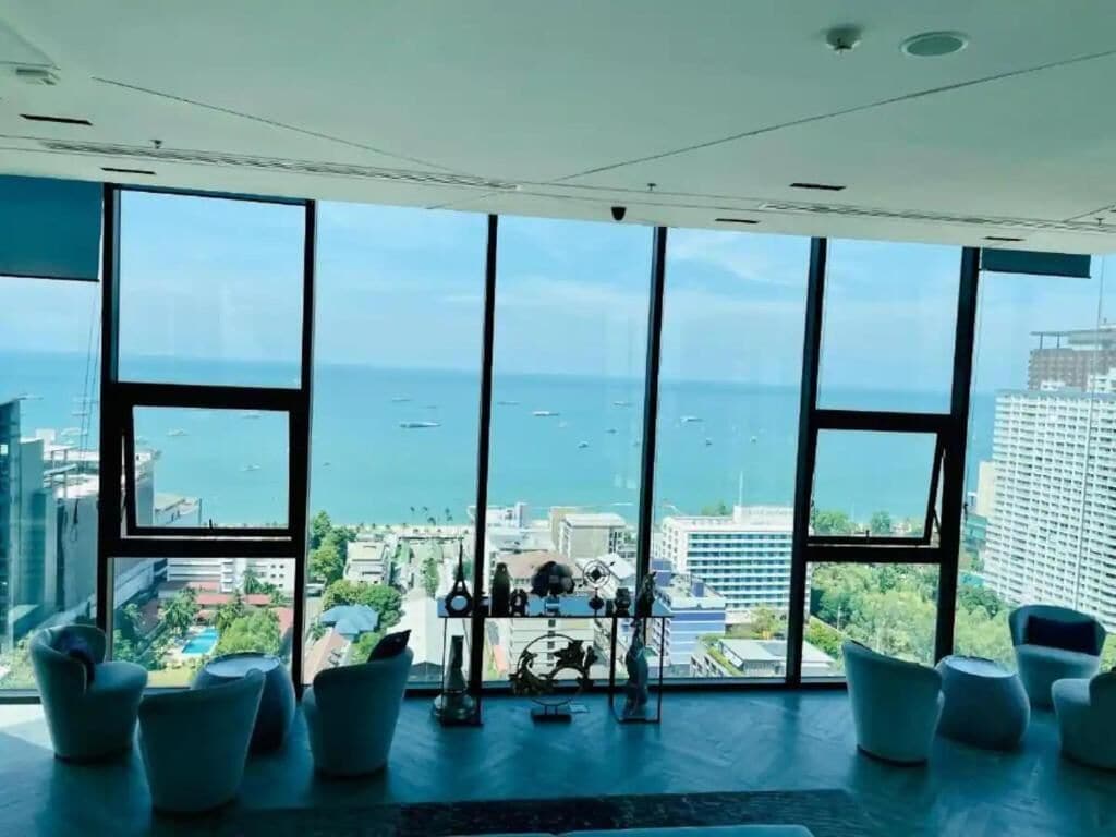 Une pièce dotée de grandes fenêtres, offrant une vue sur la mer et meublée dans un style moderne.