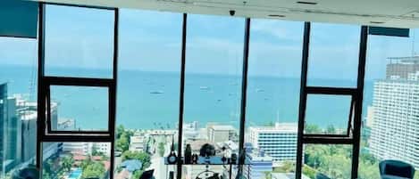 Une pièce dotée de grandes fenêtres, offrant une vue sur la mer et meublée dans un style moderne.