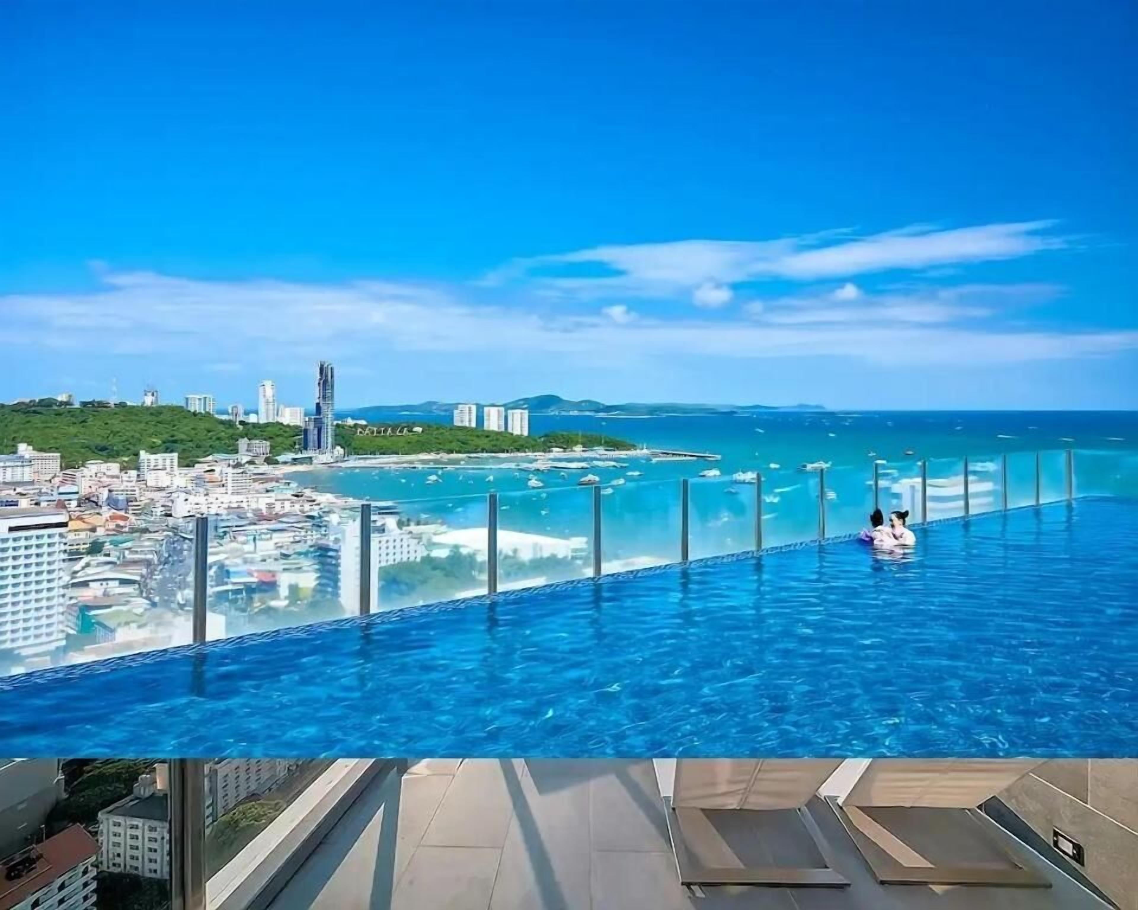 A rooftop infinity pool with a view of a coastal cityscape and the ocean.