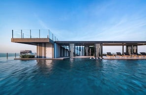 A modern infinity pool with a glass balustrade, lounge chairs, and a contemporary building structure. - 2 Bed Room Beautiful View Best of Pattaya (Pattaya)