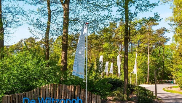 A pathway leading into a wooded area with a wooden fence and a sign that reads 'De Wittzangh'. - De Wiltzangh - Bosrand Wellness Cabin | 2p by Interhome (Ruinen)