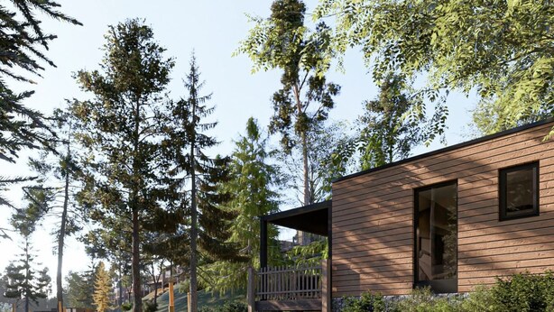 A modern wooden cabin with a deck overlooking a body of water, surrounded by trees.