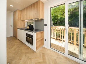 A modern kitchen with wooden cabinets, a built-in oven, and a large sliding glass door leading to a deck.