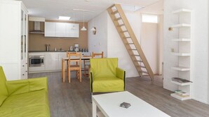 A compact living space with a kitchen, dining area, and a loft bedroom accessed by a wooden ladder. - Bungalowpark Herkingen - Casa Ina by Interhome (Herkingen)