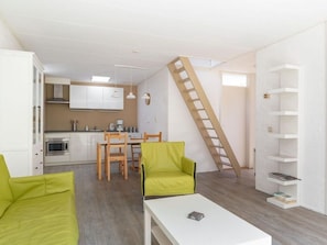 A compact living space with a kitchen, dining area, and a loft bedroom accessed by a wooden ladder. - Bungalowpark Herkingen - Casa Ina by Interhome (Herkingen)