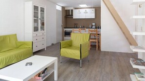 A modern apartment with a living area, a dining area, and a kitchenette. There is a staircase leading to an upper level. - Bungalowpark Herkingen - Casa Ina by Interhome (Herkingen)