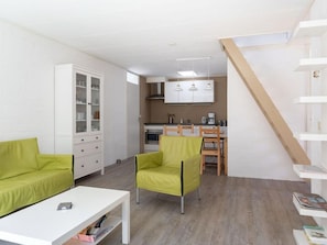 A modern apartment with a living area, a dining area, and a kitchenette. There is a staircase leading to an upper level. - Bungalowpark Herkingen - Casa Ina by Interhome (Herkingen)