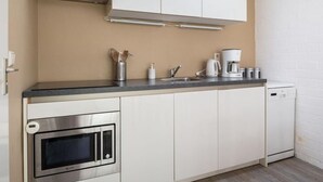 A compact kitchen with a microwave, stove, and coffee maker. - Bungalowpark Herkingen - Casa Ina by Interhome (Herkingen)