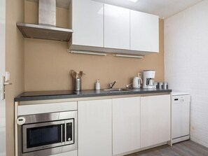 A compact kitchen with a microwave, stove, and coffee maker. - Bungalowpark Herkingen - Casa Ina by Interhome (Herkingen)