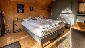 Makuuhuone, jossa on sänky, yöpöytä, lamppu ja riippuvalaisin.