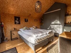 Ein Schlafzimmer mit einem Bett, einem Nachttisch, einer Lampe und einer Pendelleuchte.