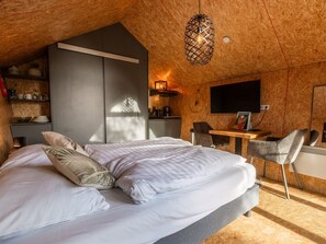 Ein Schlafzimmer mit Bett, Nachttischen, Schreibtisch, Stuhl und Fernseher.