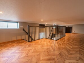 A spacious room with a wooden herringbone floor, a metal railing, and a window with blinds. - De Wiedense Meren - Villa Waterrijk | 4p by Interhome (Wanneperveen)