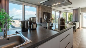 Eine moderne Küche mit einer großen Kochinsel, integrierten Geräten und Blick ins Freie.