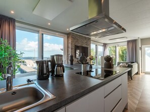 A modern kitchen with a large island, built-in appliances, and a view of the outdoors. - De Wiedense Meren - Villa Waterrijk | 4p by Interhome (Wanneperveen)