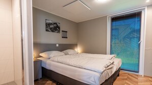 Ein Schlafzimmer mit Bett, Nachttischen, Wandbild und einem Fenster mit Jalousien.