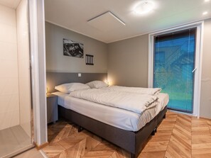 A bedroom with a bed, bedside tables, a wall-mounted artwork, and a window with blinds. - De Wiedense Meren - Villa Waterrijk | 4p by Interhome (Wanneperveen)