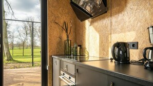 A modern kitchen with a large window, a coffee maker, and a view of a park. - Vakantiepark Aan de Maas - Weide Lande | 4p by Interhome (Kerkdriel)