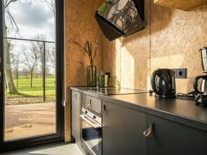 Una cocina moderna con un ventanal grande, cafetera y vista a un parque.