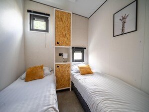 Un dormitorio con dos camas, un armario de madera, una ventana y un cuadro de una jirafa en la pared.