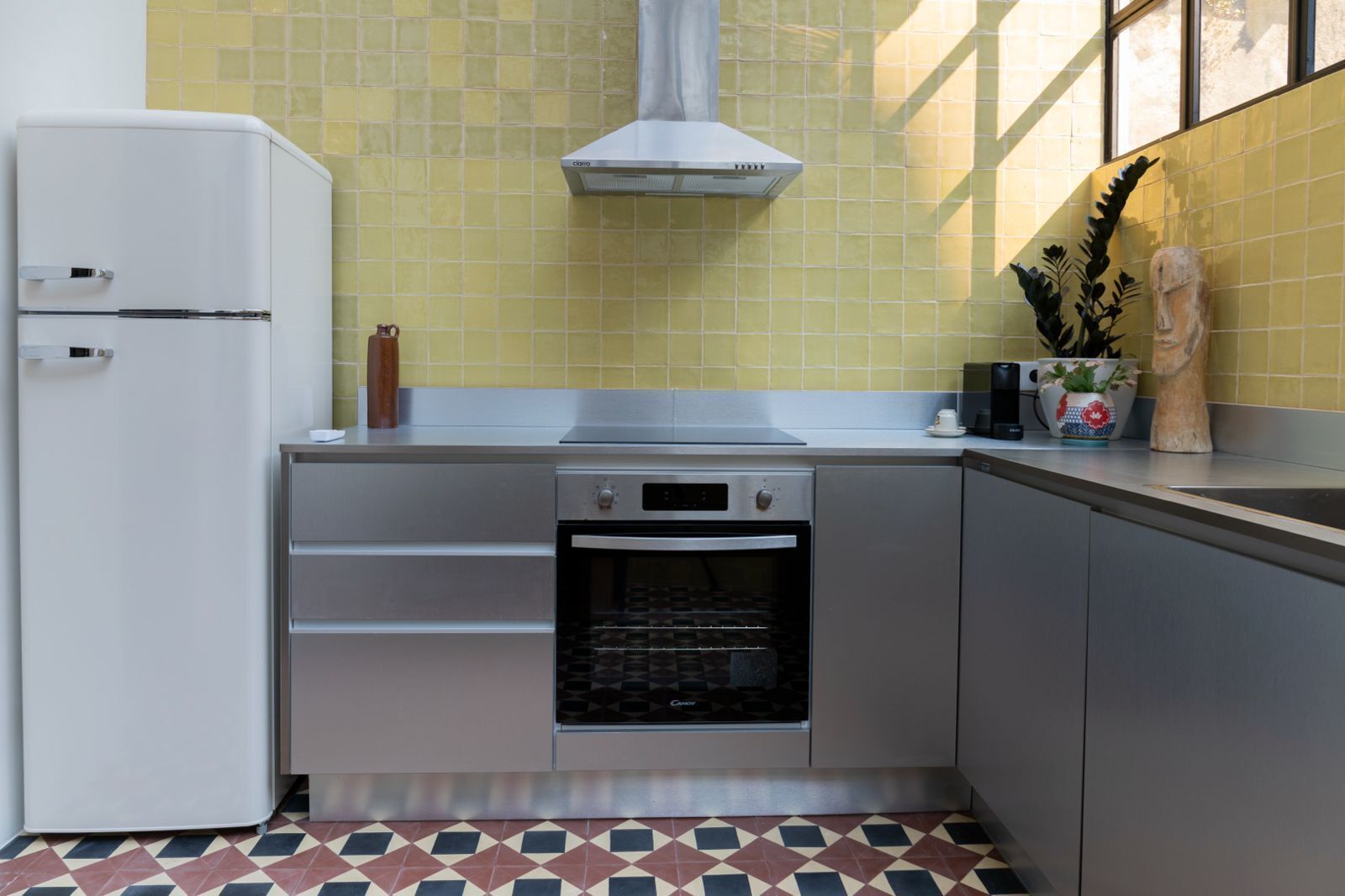 A compact kitchen with a built-in oven, a stainless steel range hood, and a white refrigerator.