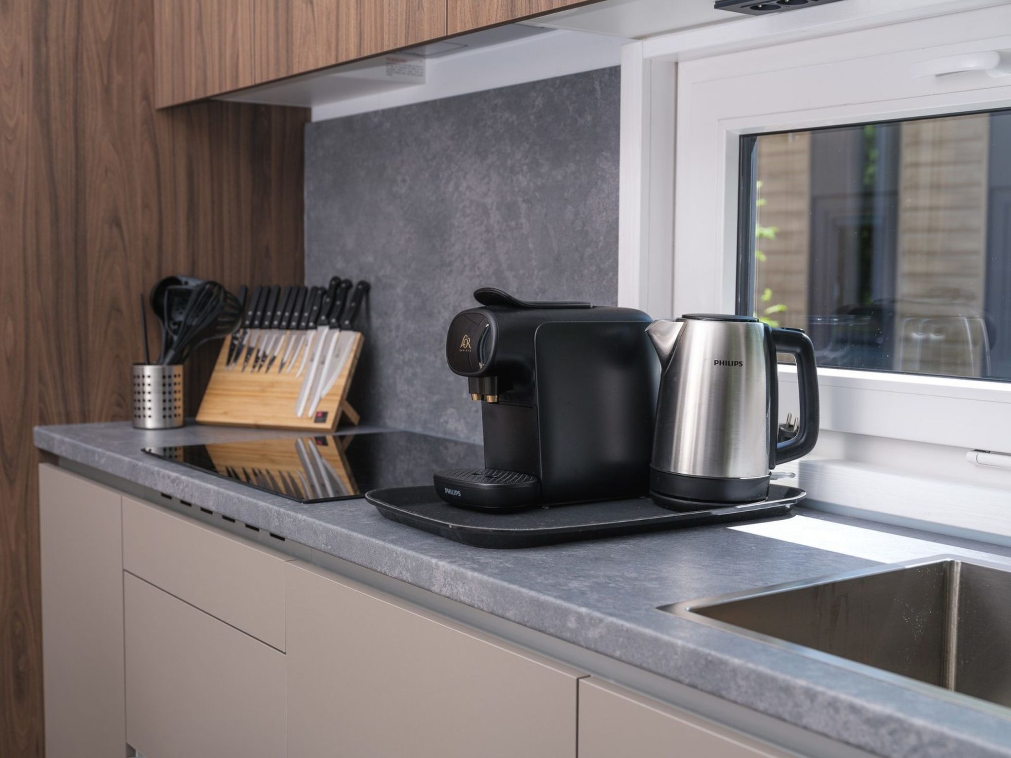 A kitchen with a coffee maker, a kettle, and a knife block.