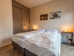 Ein Schlafzimmer mit einem Bett, zwei Nachttischen mit Lampen, einem Kleiderschrank und zwei Wandbildern.