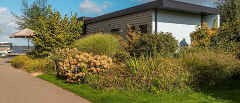 A modern building with a flat roof, surrounded by well-maintained greenery and a paved walkway.