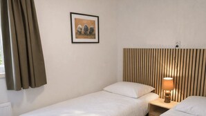 A single-bed room with a headboard, a bedside lamp, and a framed picture on the wall. - De Wiltzangh - Boschborg Lodge | 4p by Interhome (Ruinen)
