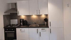 A modern kitchen with white cabinets, a gas stove, a coffee maker, and a sink. - De Wiltzangh - Boschborg Lodge | 4p by Interhome (Ruinen)