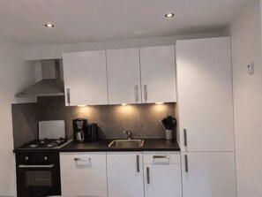A modern kitchen with white cabinets, a gas stove, a coffee maker, and a sink. - De Wiltzangh - Boschborg Lodge | 4p by Interhome (Ruinen)