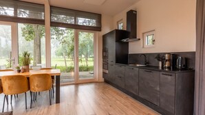 A modern kitchen with a large window, a dining area with chairs, and a view of the outdoors. - Vakantiepark Aan de Maas - Weide Lande | 6p by Interhome (Kerkdriel)