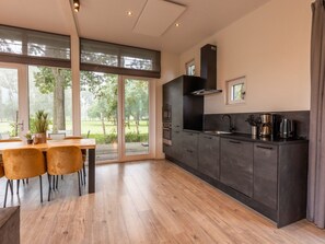 A modern kitchen with a large window, a dining area with chairs, and a view of the outdoors. - Vakantiepark Aan de Maas - Weide Lande | 6p by Interhome (Kerkdriel)