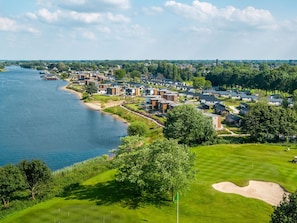A coastal residential area with modern houses, a golf course, and a river. - Vakantiepark Aan de Maas - Weide Lande | 6p by Interhome (Kerkdriel)