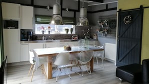 A modern kitchen with a dining area, featuring a large island, pendant lights, and a brick backsplash. - Wilsumer Berge Resort - Green Forest by Interhome (Wilsum)