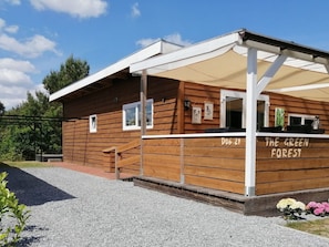 Eine Holzhütte mit überdachter Veranda, mit der Aufschrift 'D06-21' und 'DER GRÜNE WALD'.