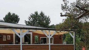 A wooden building with a covered porch and a garden in front. - Wilsumer Berge Resort - Green Forest by Interhome (Wilsum)