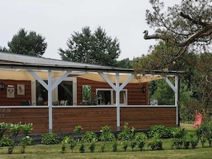 Ein Holzhaus mit überdachter Veranda und einem Garten davor.