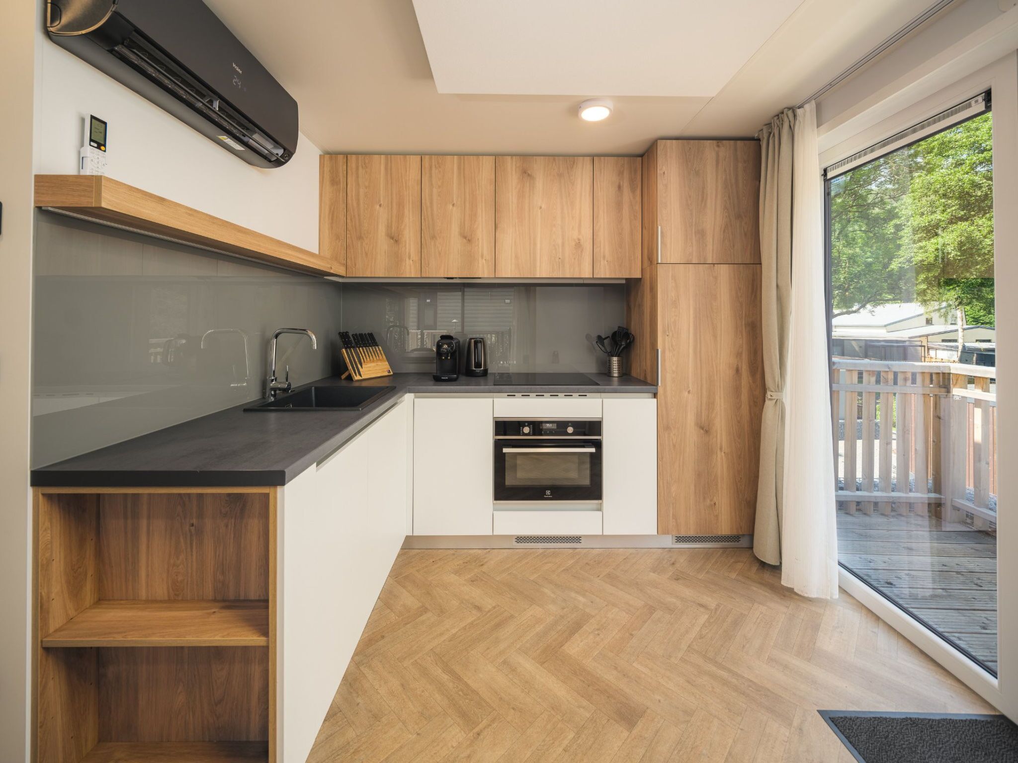A modern kitchen with wooden cabinets, a black countertop, and a built-in oven.